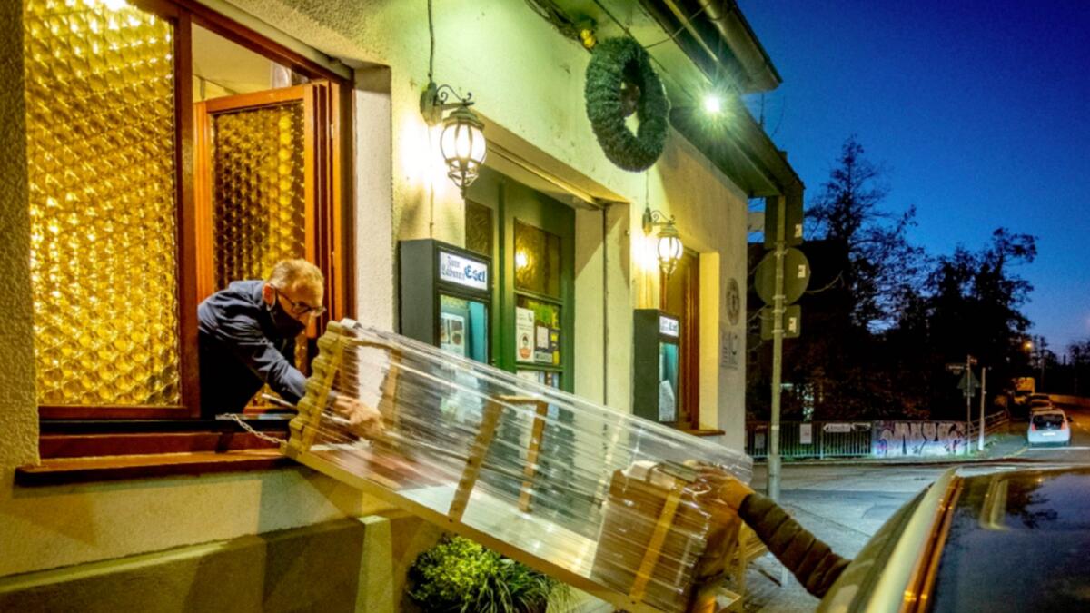 A box with food slides down to car from a window of the apple cider restaurant 'Zum Lahmen Esel' in Frankfurt, Germany. Due to the new partial lockdown to avoid the coronavirus spread the restaurant offers cider and food to go in a self-made drive through set up. — AP