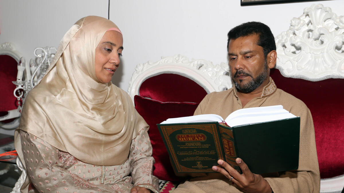 Tauseef reads the Holy Quran as his wife looks on.