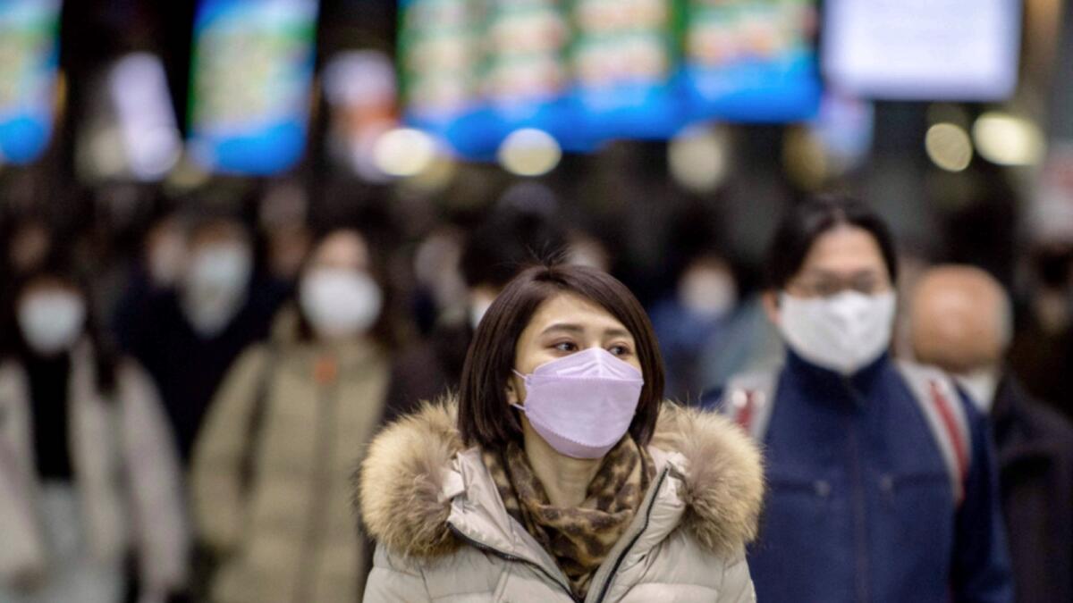 People wearing face masks walk at Shinagawa station in Tokyo. — AFP