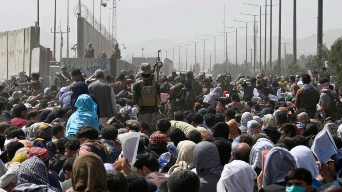 Afghans gather on a roadside near the military part of the airport in Kabul, hoping to flee from the country. — AFP