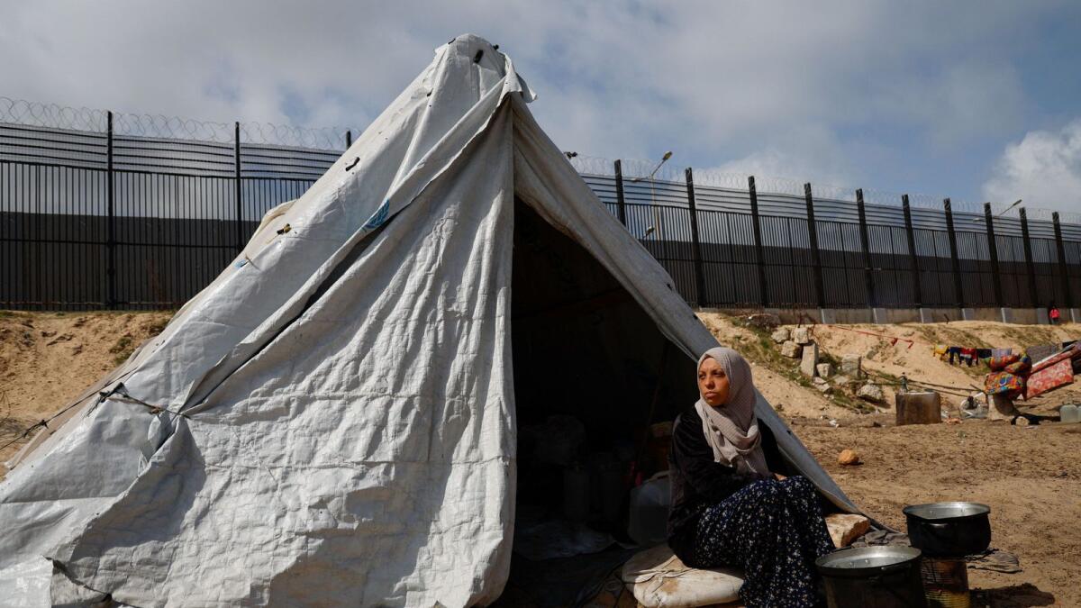 A woman sits next to a tent in Rafah. — Reuters