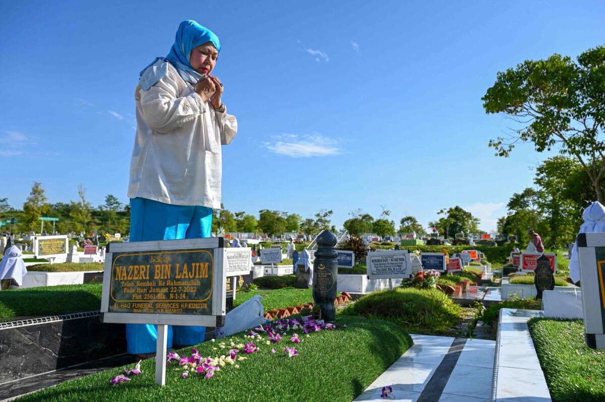 This photo taken on May 1, 2023 shows Nazira Lajim Hertslet, the sister of Nazeri Lajim, who was executed for drugs trafficking, praying by his grave at a Muslim cemetery in Singapore. -- AFP