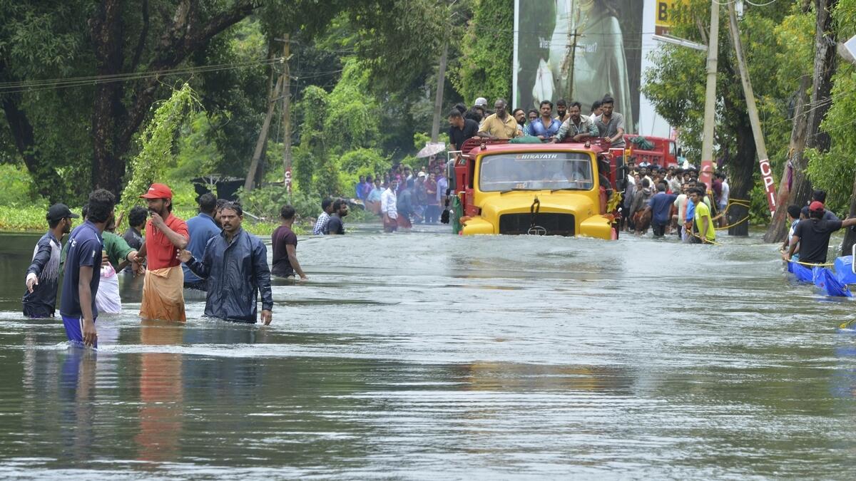 A truck carries people past a flooded road in Thrissur, in the southern Indian state of Kerala.- AP