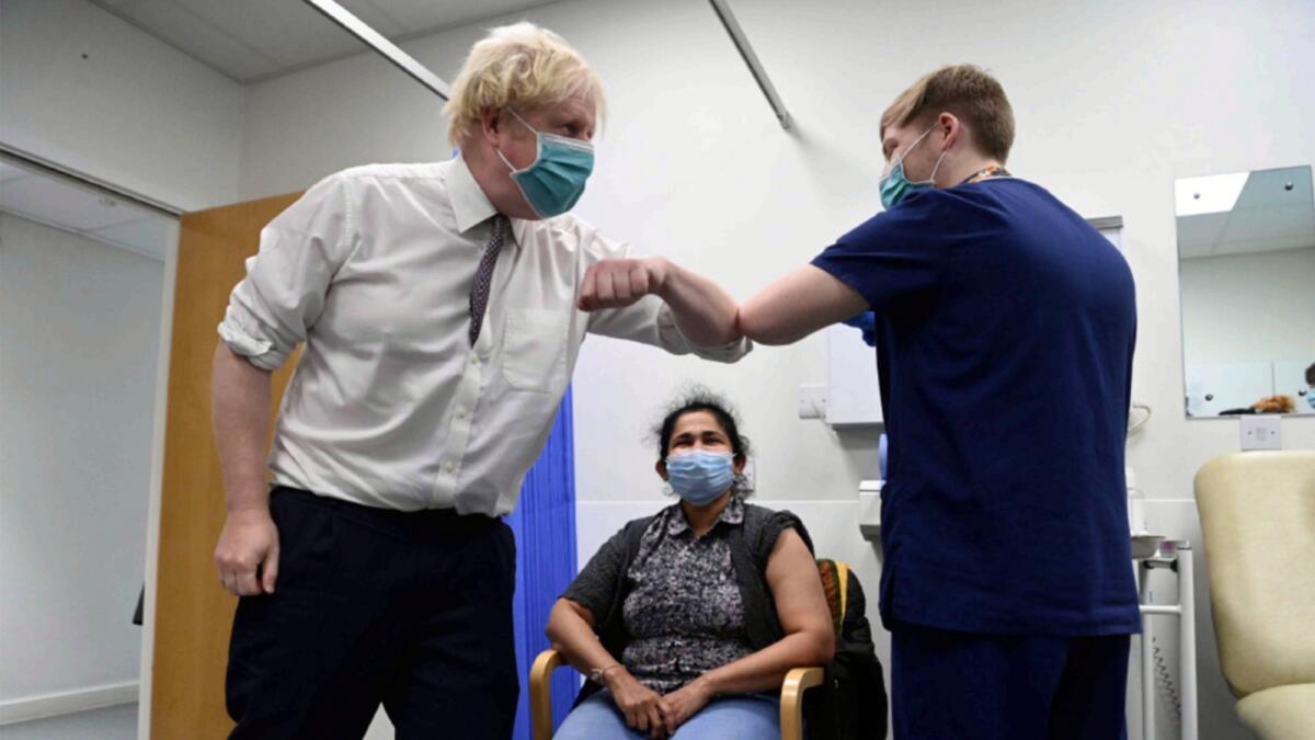 British Prime Minister Boris Johnson bumps elbows with a medic as a patient receives a Covid-19 vaccine in London. — AP