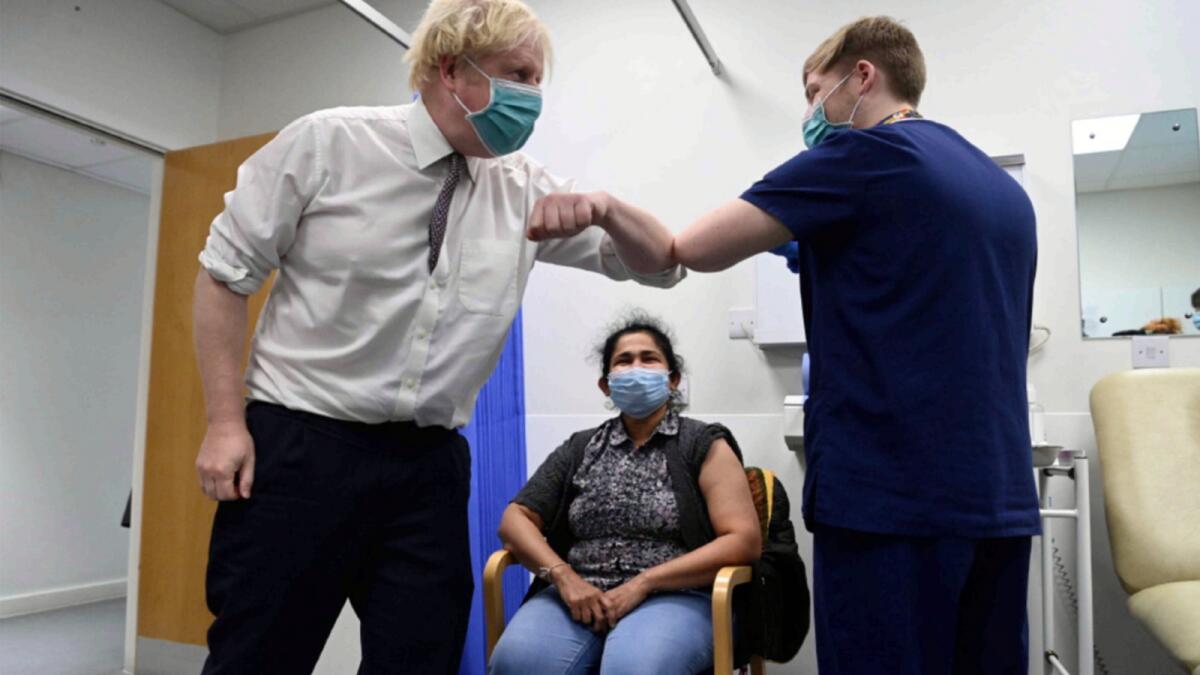 British Prime Minister Boris Johnson bumps elbows with a medic as a patient receives a Covid-19 vaccine in London. — AP