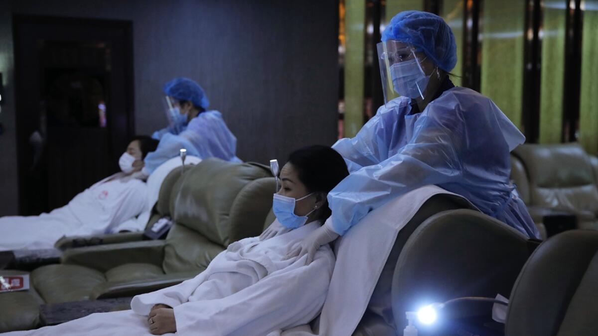 Staff members wearing protective suits demonstrate their safety measures to media as they hope the government allowing their massage parlours to reopen in Hong Kong. Businesses such as massage parlours was forced to close to prevent the spread of Covid-19  as part of social distancing measures. The city's economy contracted 9 per cent in the second quarter of this year, marking a full year of recession due to last year's anti-government protests and the pandemic. Photo: AP