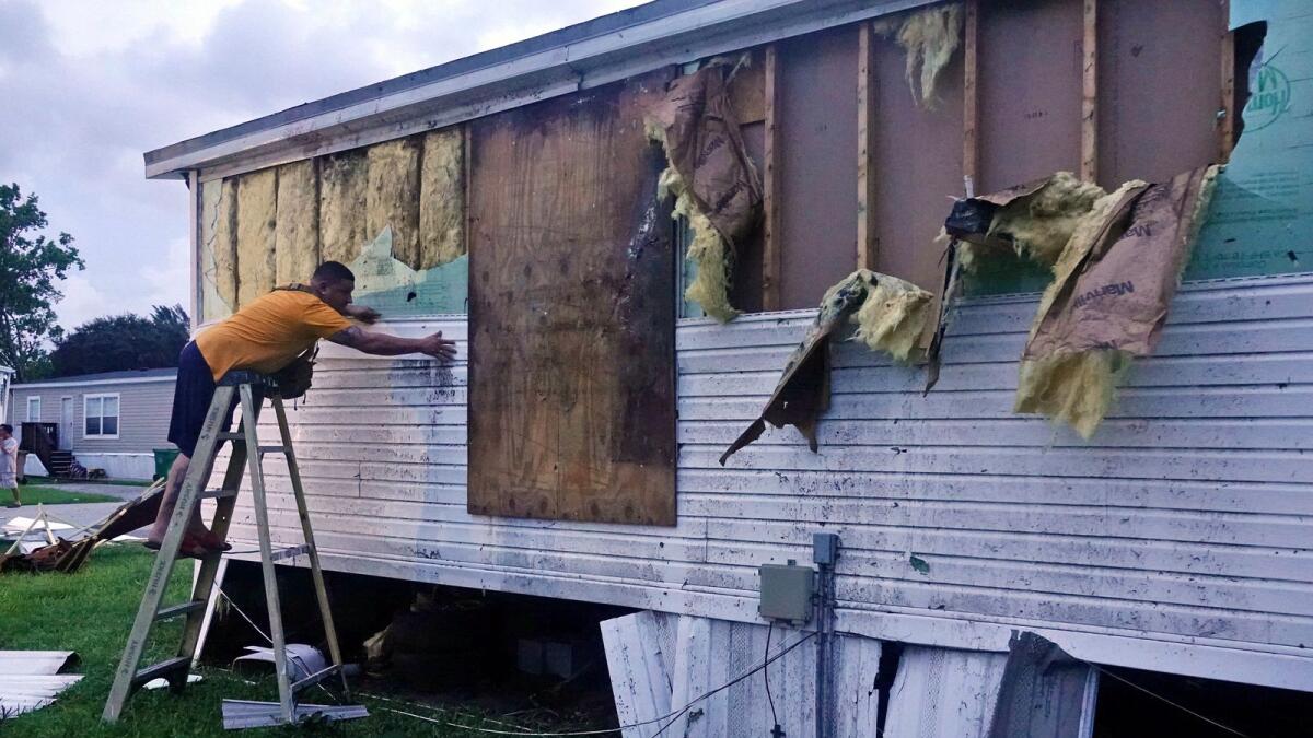 A man repairs damage at his mobile home in Davie, Florida. – AP