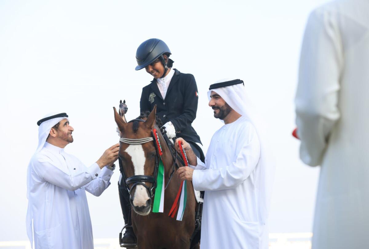 Sheikh Haitham bin Saqr Al Qassimi (L) handing over a trophy to Shamsa (C) and Sultan Khalifa Al Yahya’ie, Director General of Sharjah Equestrian and Racing Club looking on (R).