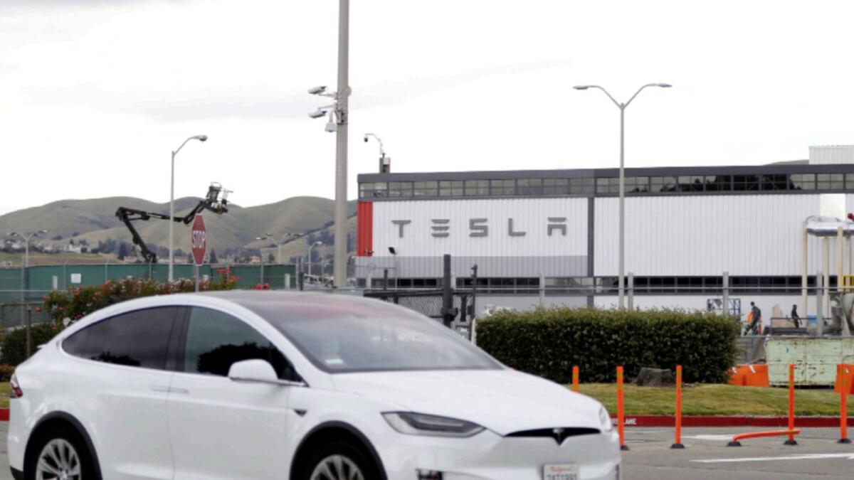 A Tesla vehicle drives past Tesla's primary vehicle factory in California. — Reuters file
