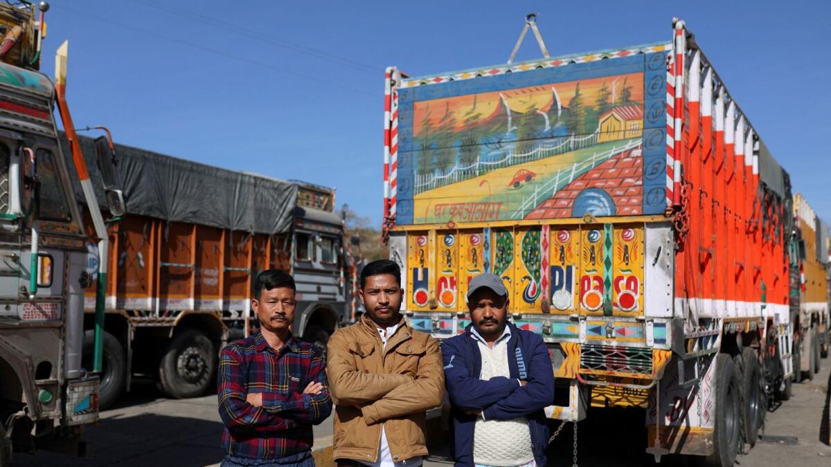 Truck drivers Lal Singh, Vijay Mehra and Tilak Raj pose for a picture near parked trucks next to the Ambuja Cements Limited plant owned by Adani Group in Darlaghat, Solan district in the state of Himachal Pradesh, India, on February 16, 2023. — Reuters