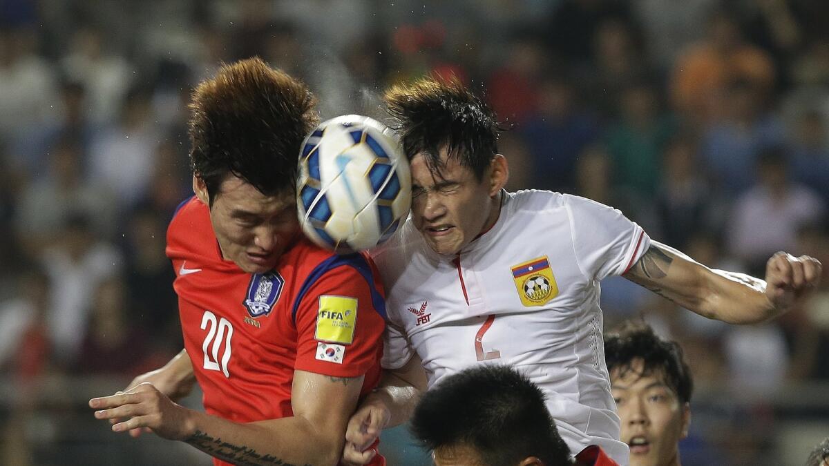 South Korea’s Jang Hyun-soo (left) heads the ball with Laos’s Vongchiengkham Soukaphone during their Asian Zone Group G qualifying match on Thursday. South Korea won 8-0. 