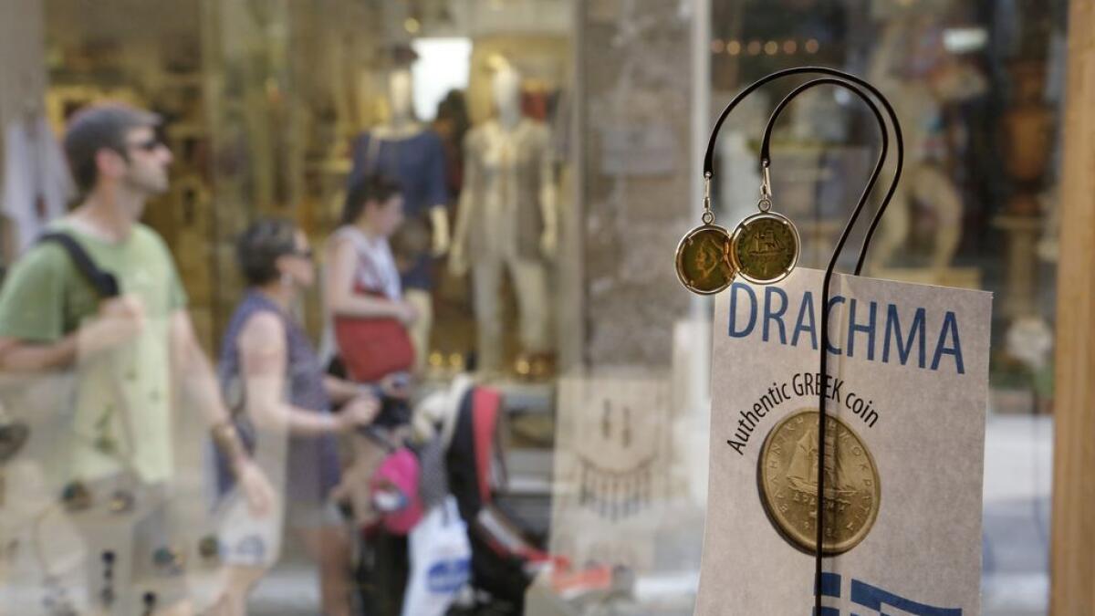 Tourist pass by storefront displaying jewellery made from old drachma coins in the historic Plaka district of central Athens.