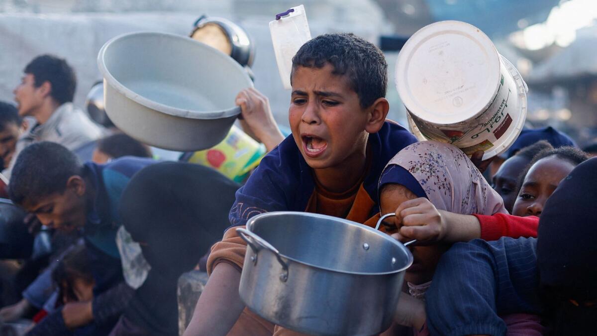 A child reacts as Palestinians wait to receive food during the holy month of Ramadan in Rafah. — Reuters