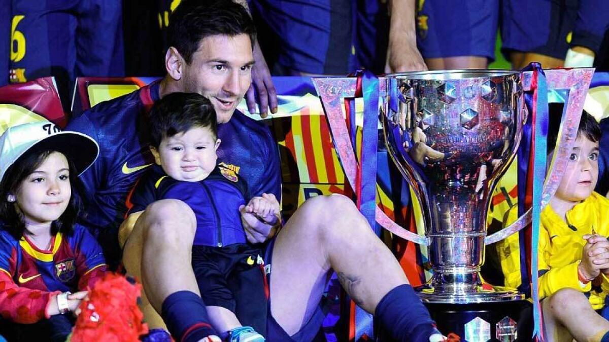Messi sits with his young son Thiago as Barcelona celebrate winning the Spanish title at the end of the 2012-13 season.