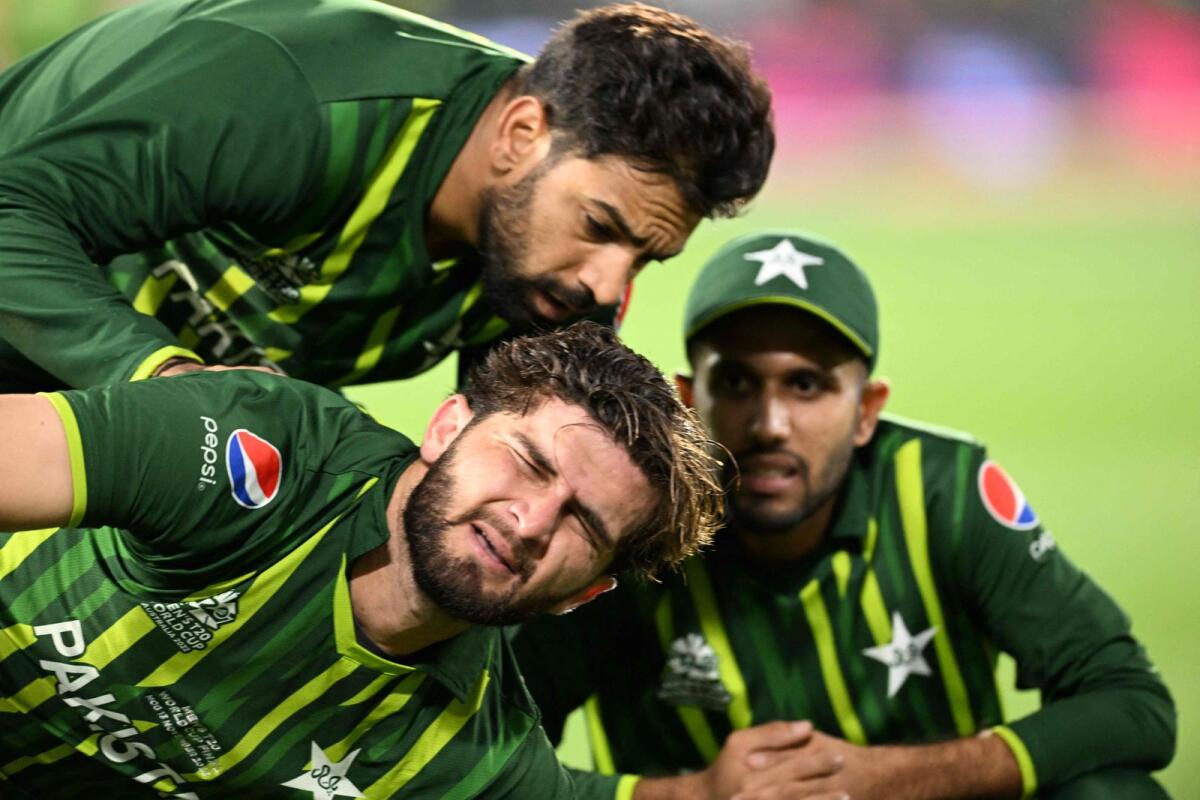 Pakistan's Shaheen Shah Afridi (centre) writhes in pain after suffering an injury while taking a catch to dismiss England's Harry Brook during the final in Melbourne on Sunday. — AFP