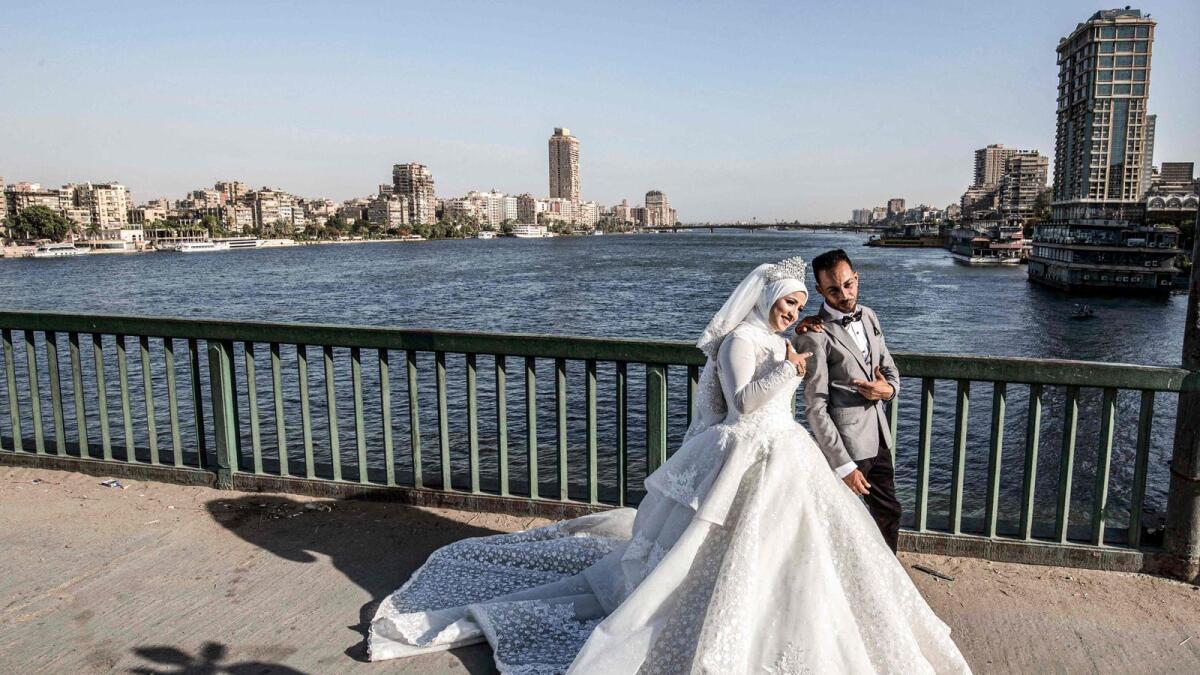 A couple poses before a video cameraman for their wedding video along the Cairo University connecting Cairo with its twin city of Giza on June 11, 2020. -- AFP