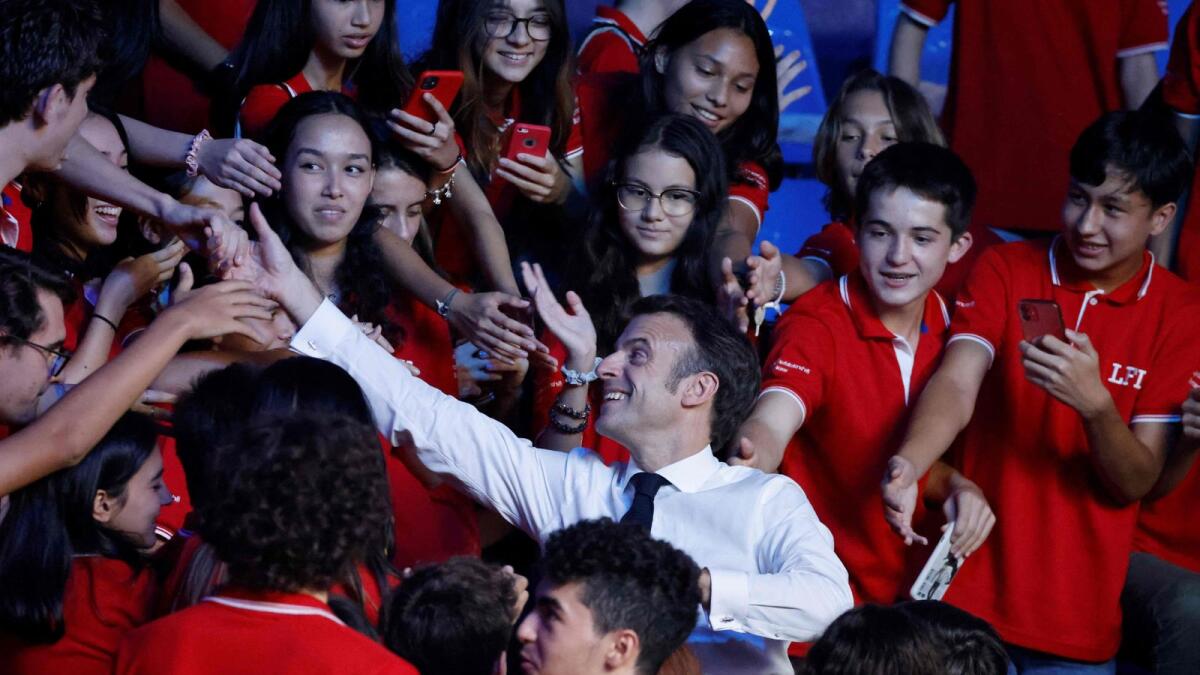 French President Emmanuel Macron (centre) speaks with high school students during a visit to Rajadamnern Muay Thai Stadium in Bangkok on Thursday. — AFP