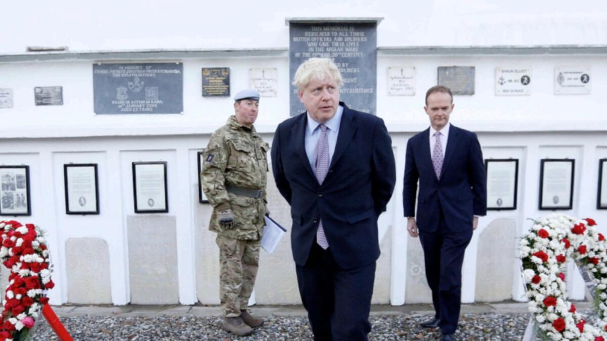 Britain's Foreign Secretary Boris Johnson (C) and British ambassador to Afghanistan Dominic Jermey (R) visit the British cemetery in the Afghan capital Kabul in 2016. — AFP file