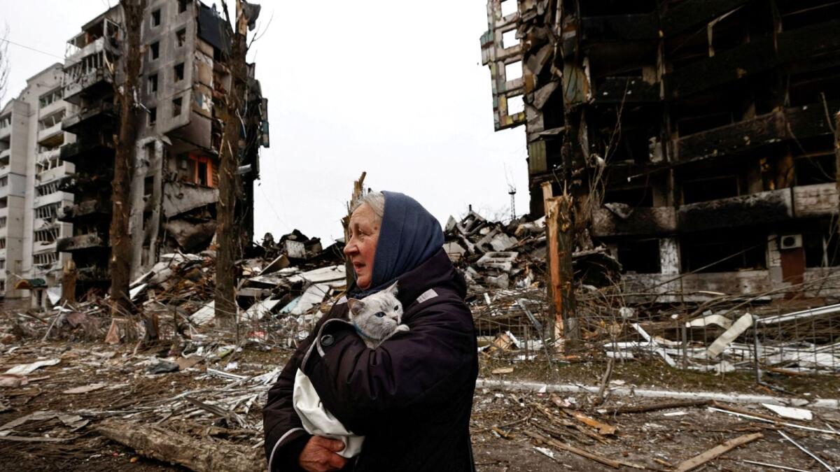 A woman carries her cat as she walks past buildings that were destroyed by Russian shelling, in the Kyiv region, Ukraine, April 5, 2022. (Photo: Reuters)