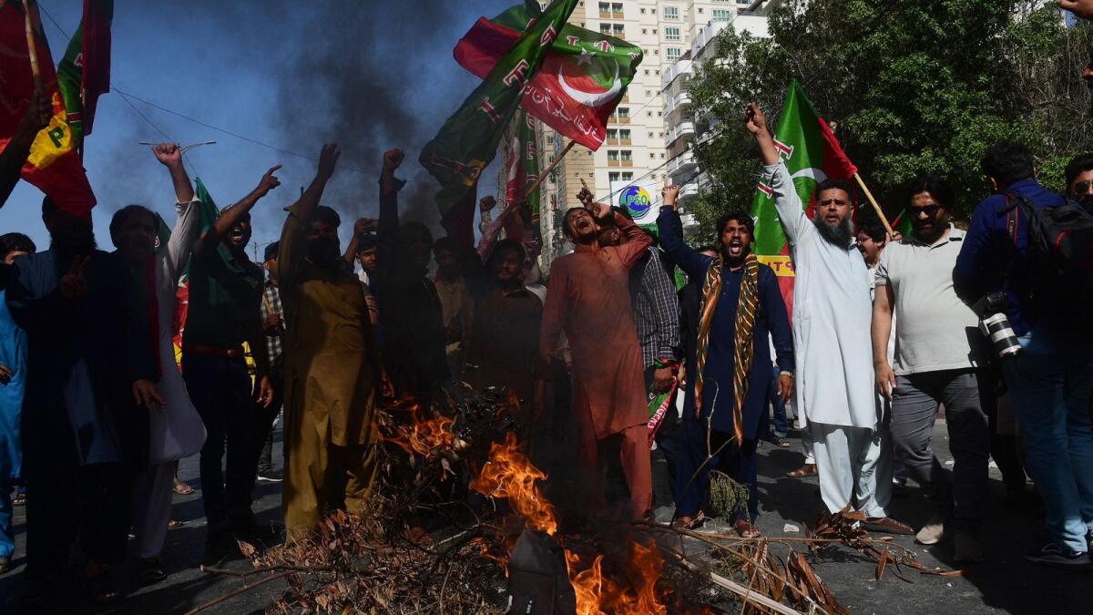 Pakistan Tehreek-e-Insaf party activists and supporters of former Pakistan's Prime Minister Imran shout slogans next to a fire as they block a road during a protest against the arrest of their leader in Karachi on May 9.  — AFP