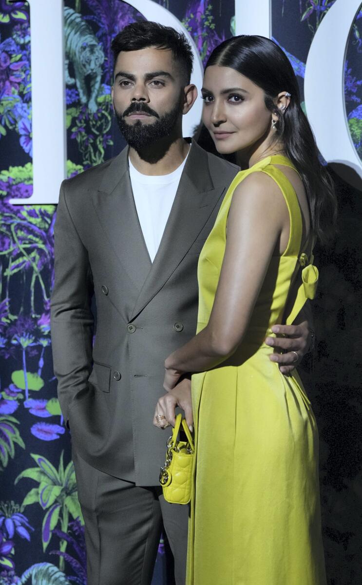 Anushka in a beautiful yellow dress and a matching Lady Diana mini bag. She kept her tresses open for the look. Virat, on the other hand, looked handsome in a khaki-toned suit and white shirt. He completed his stylish look with comfy white sneakers.