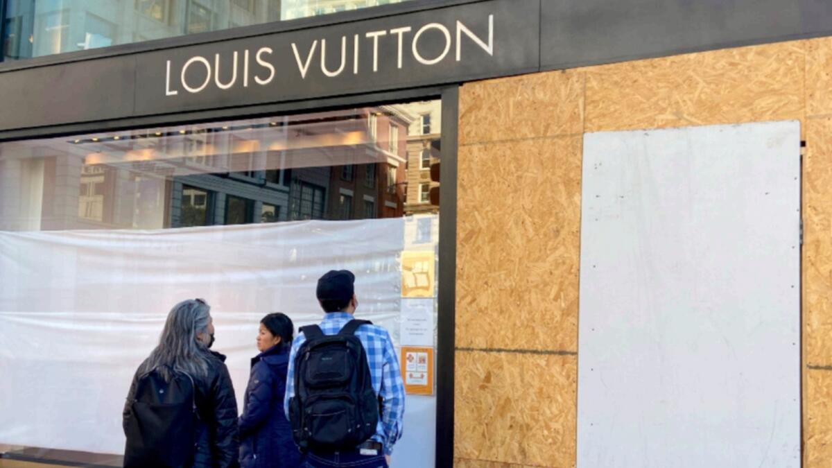 Union Square visitors look at damage to the Louis Vuitton store after looters ransacked businesses late Saturday night in San Francisco. — AP