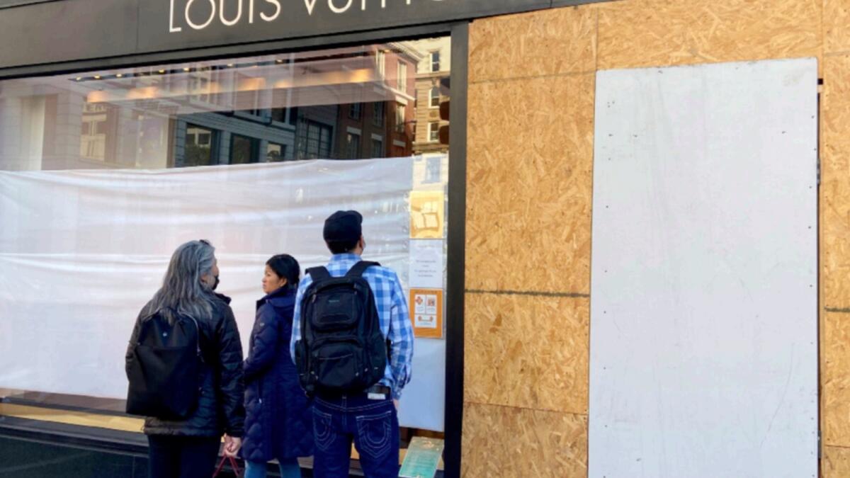 Union Square visitors look at damage to the Louis Vuitton store after looters ransacked businesses late Saturday night in San Francisco. — AP