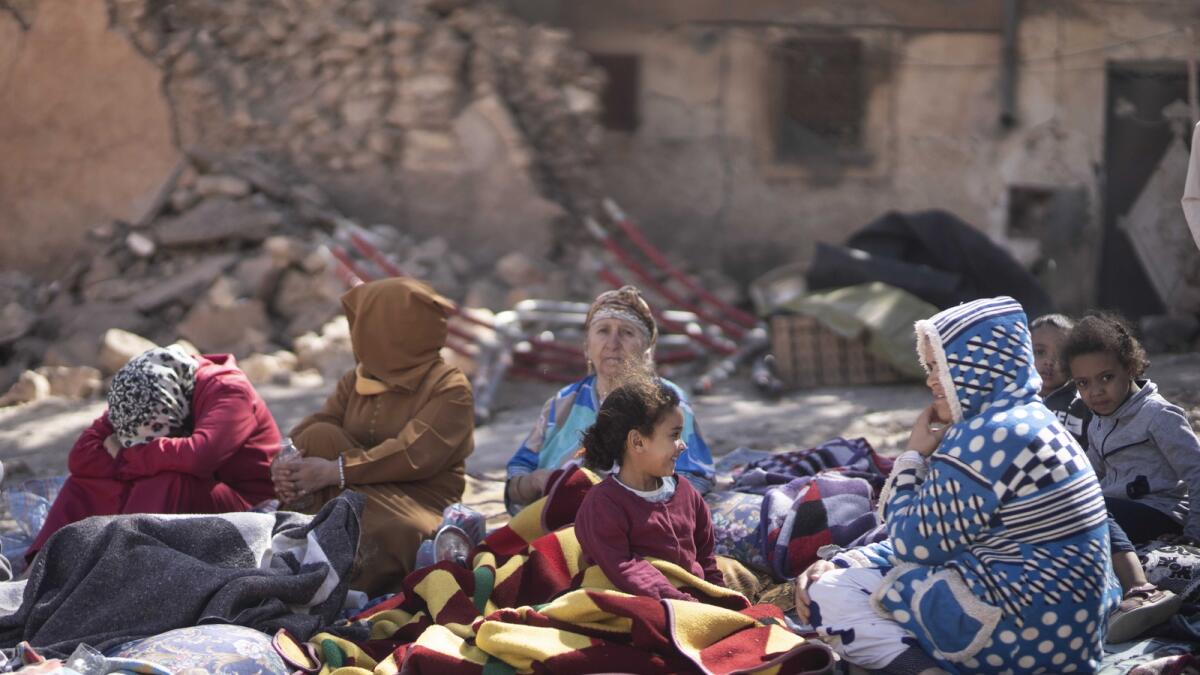 Families sit outside their destroyed homes after an earthquake in Moulay Brahim village, near Marrakech. — AP