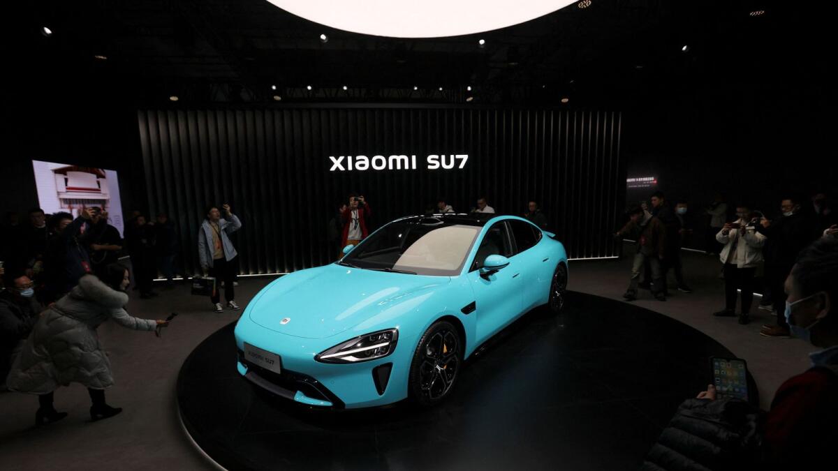 Visitors film around Xiaomi's first electric vehicle, the SU7, displayed at an event in Beijing on Thursday. — Reuters