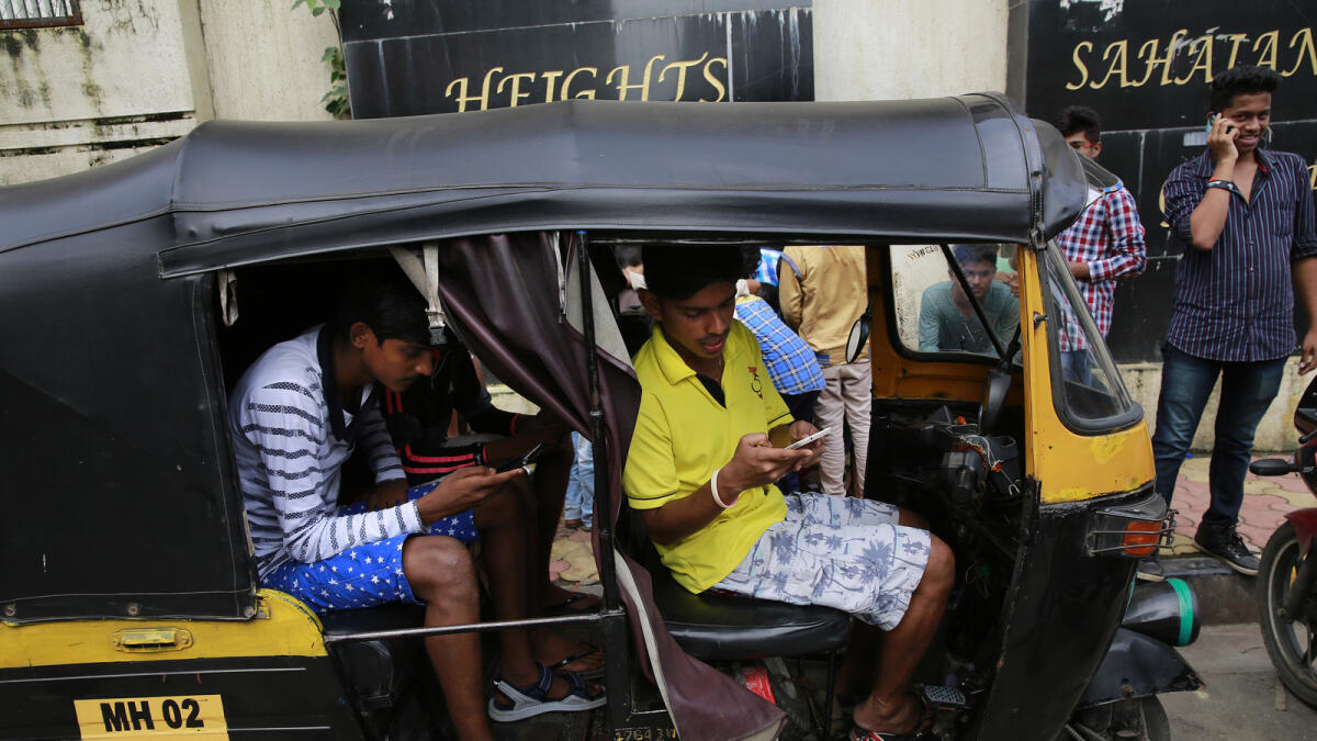 In this Sunday, July 24, 2016 photo, Indians sit inside an autorickshaw and play 'Pokemon Go' in Mumbai, India. 'Pokemon Go,' the highly addictive online game, has landed in India and thousands are out searching for pokemon characters as the mania spreads. Although it has not been launched officially in India, the augmented-reality-based game has caught on, with fans also using virtual private networks (VPNs) to change their locations and catch pokemons in New York and London while sitting in their Indian homes. (AP Photo/Rafiq Maqbool)
