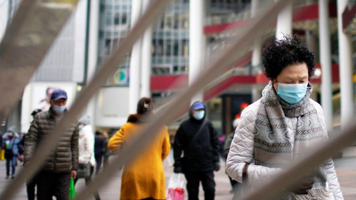 FILE PHOTO: People wearing face masks following the coronavirus disease (COVID-19) outbreak walk on a shopping street in Shanghai, China, December 14, 2021. REUTERS/Aly Song