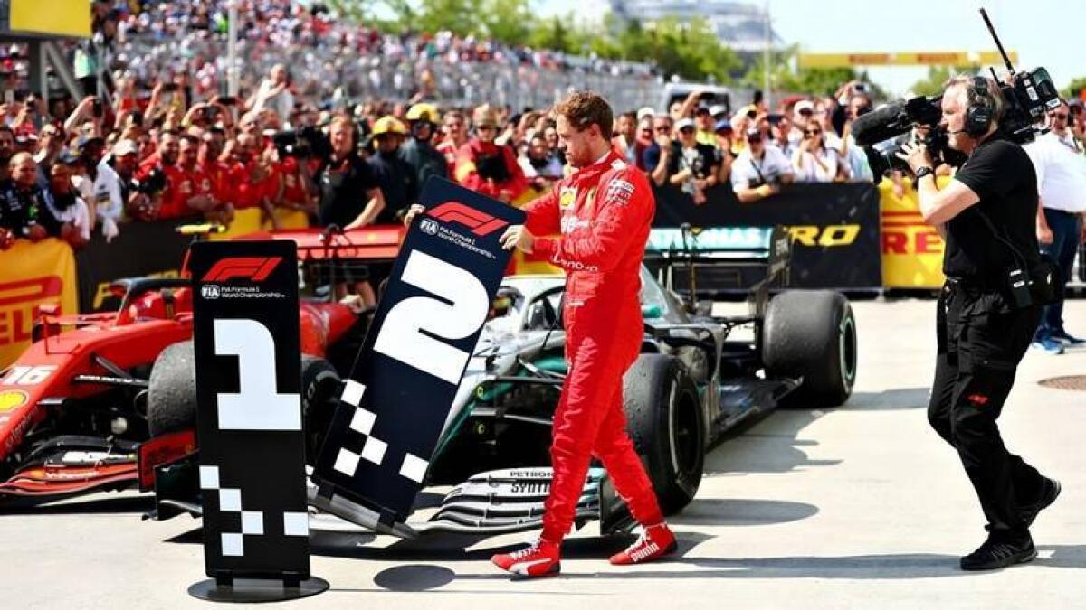 Second placed Sebastian Vettel of Ferrari swaps the number boards at parc ferme during the F1 Grand Prix of Canada. - AFP file