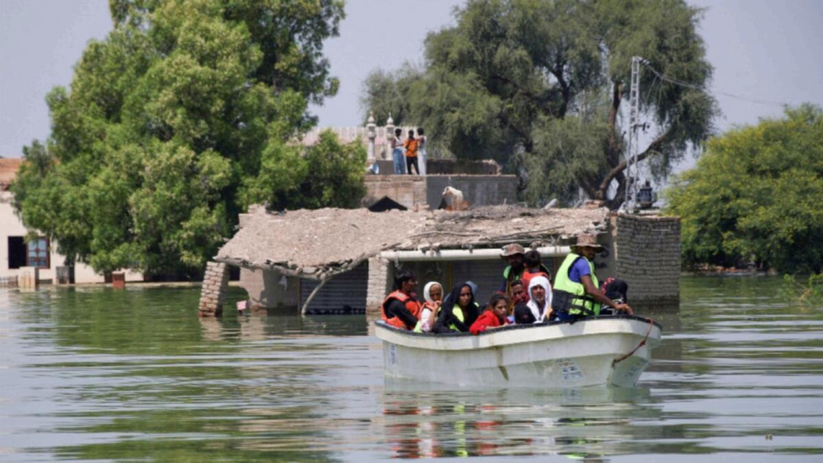Rescued flood victims sit in a boat, following rains and floods during the monsoon season in village Arazi, in Sehwan. — Reuters