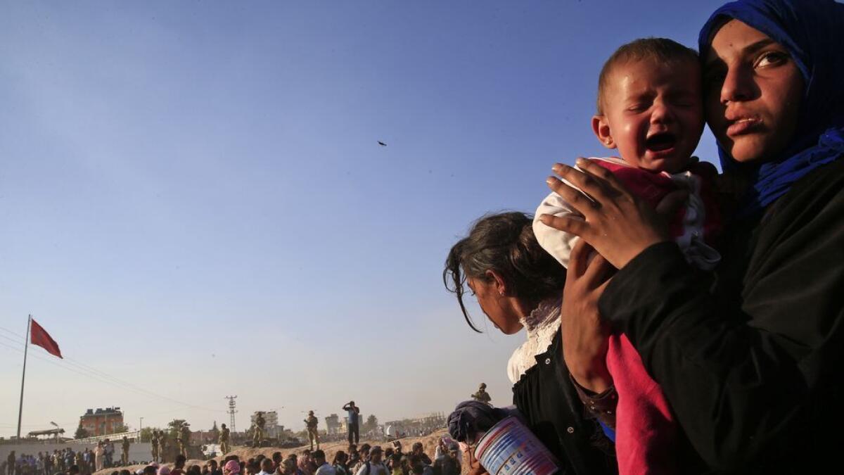 a Syrian refugee holds her baby after crossing into Turkey from Syria in Akcakale.