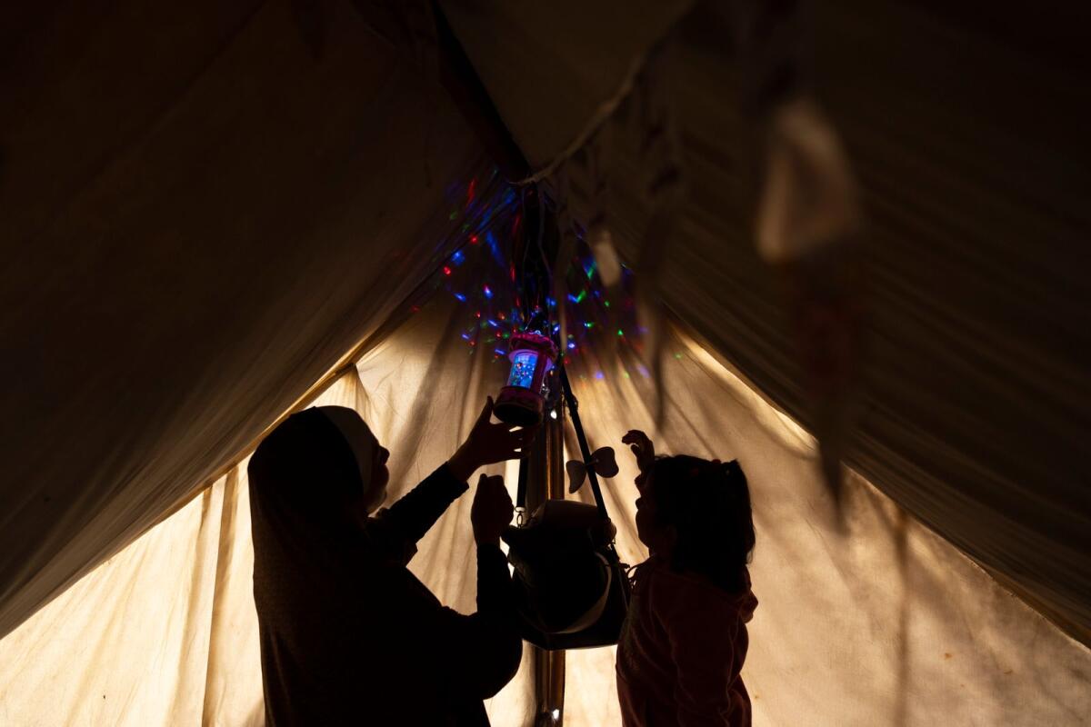 Randa Baker, who was displaced by the Israeli bombardment of the Gaza Strip, hangs Ramadan decorations and lanterns with her daughter, remarking the beginning of the holy fasting month of Ramadan at a makeshift tent camp in the Muwasi area, southern Gaza, March 11, 2024. — AP