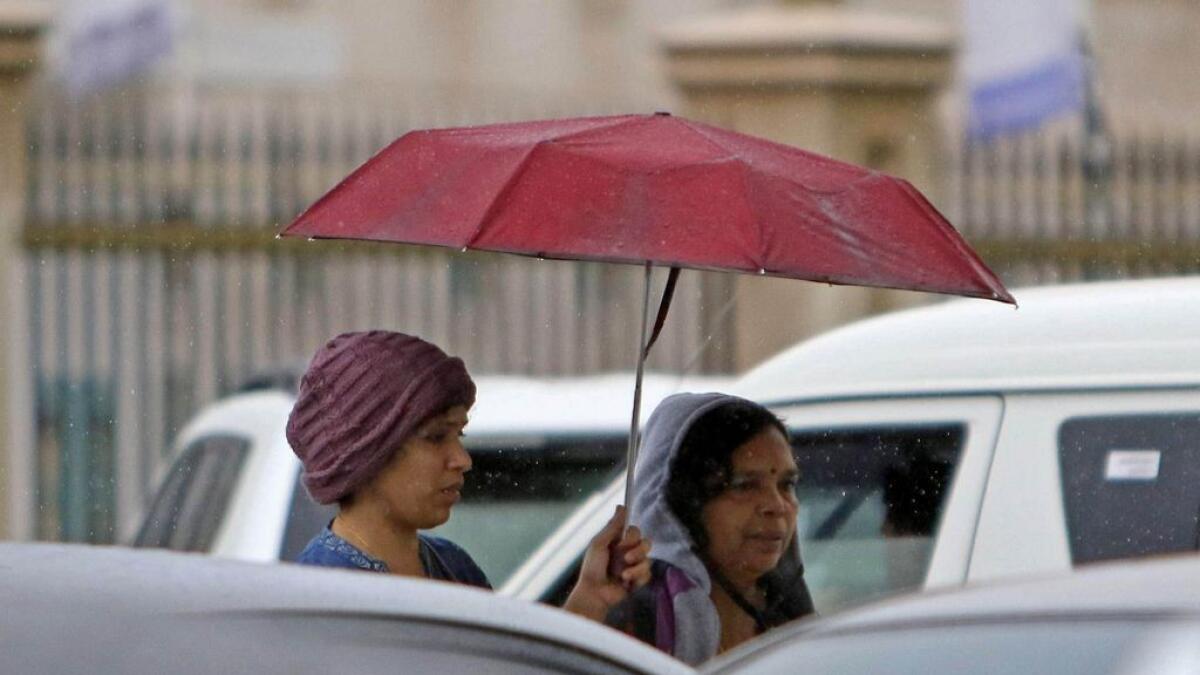 Ladies huddle under the umbrella to avoid the early morning rain at the Al Mahatta area in Sharjah.– Photo by M.Sajjad/Khaleej Times