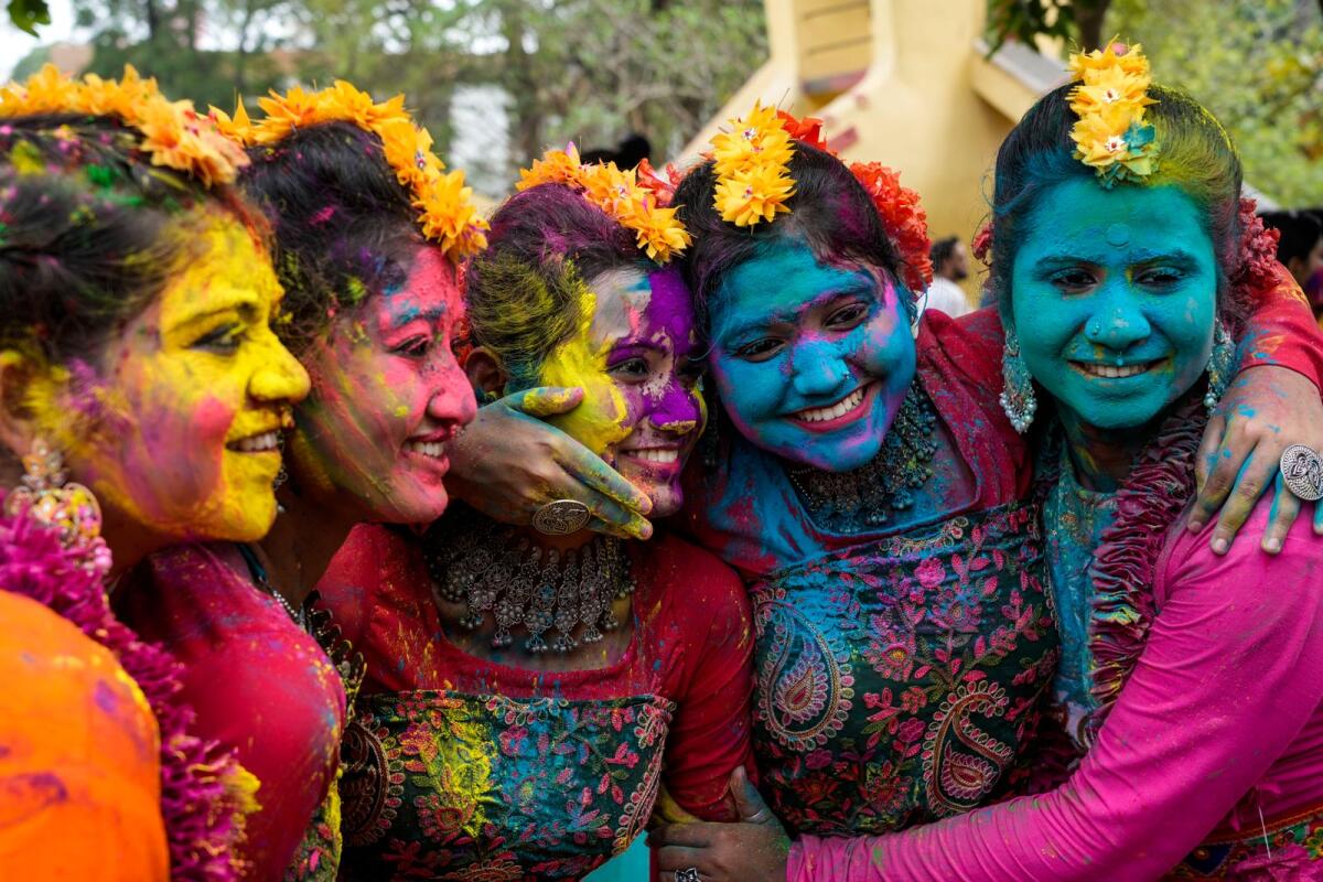 Women, with their faces smeared with coloured powder, pose for a photograph as they celebrate Holi, the festival of colors, in Kolkata, India, on Monday. — AP