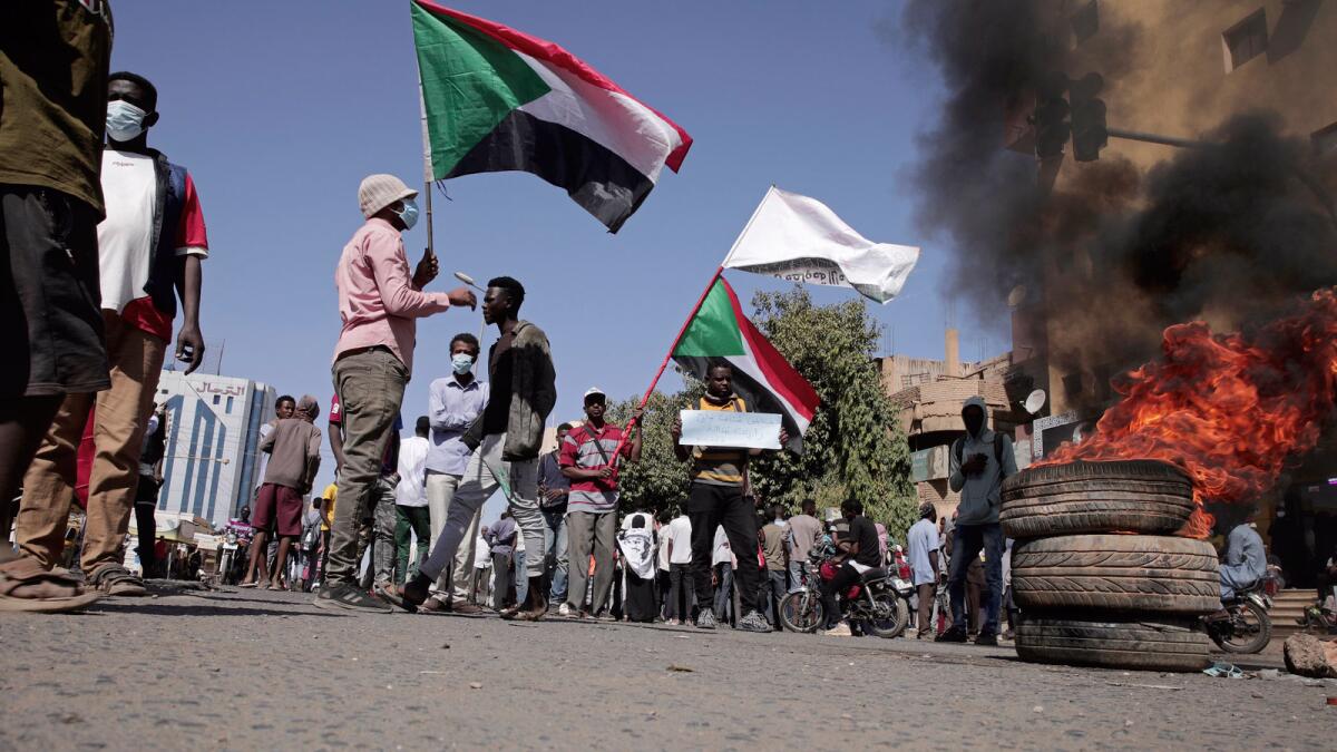 People chant slogans and burn tires during a protest to denounce the October 2021 military coup, in Khartoum, Sudan. — AP