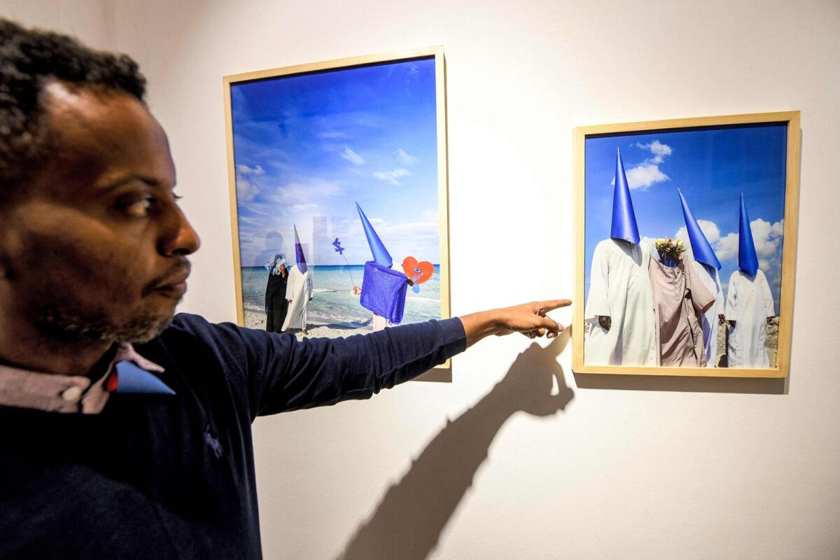 Sudanese photographer Hashim Nasr points at one of his pictures during an exhibition concert at the Goethe institute in the Egyptian capital Cairo on November 26, 2023.  — AFP