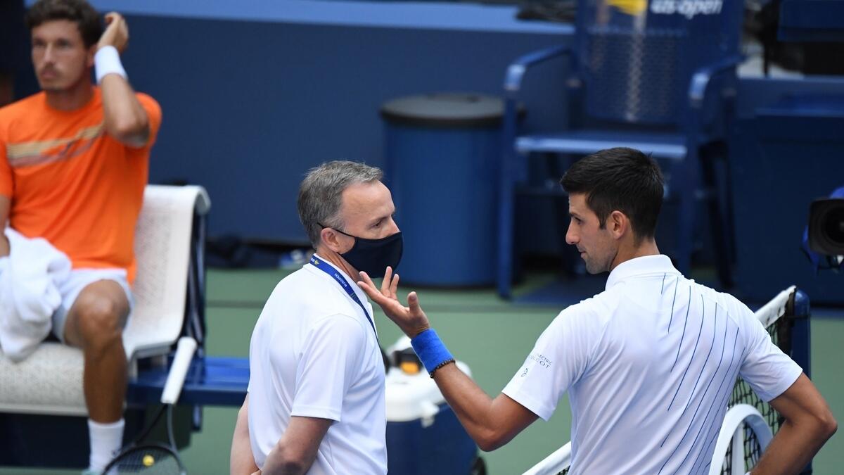 Novak Djokovic of Serbia discusses with a tournament official after being defaulted for striking a lines person with a ball