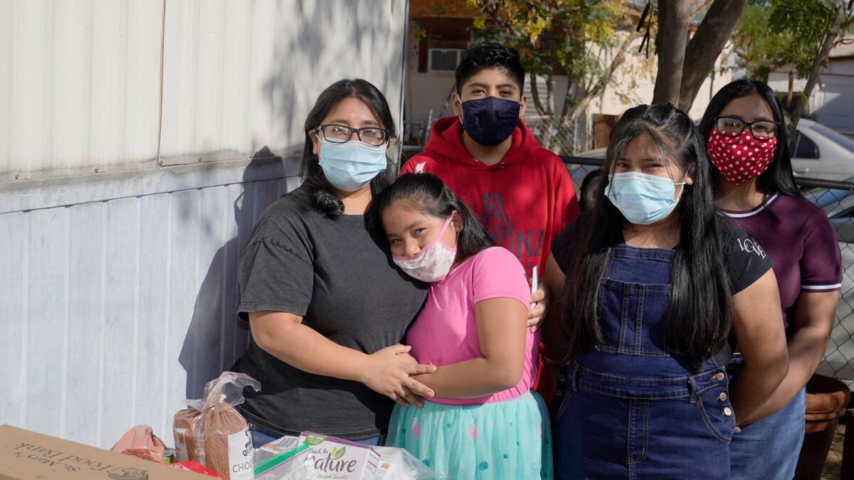 From left to right, Abigail Leocadio, stands with her children Areli, 9, Eliel, 12, Zeret, 10, and Samai, 15, after a delivery food and other resources from the Emmaus House food pantry as families struggle during the economic downturn during the Covid-19 pandemic  on Nov. 14, 2020, in Phoenix.