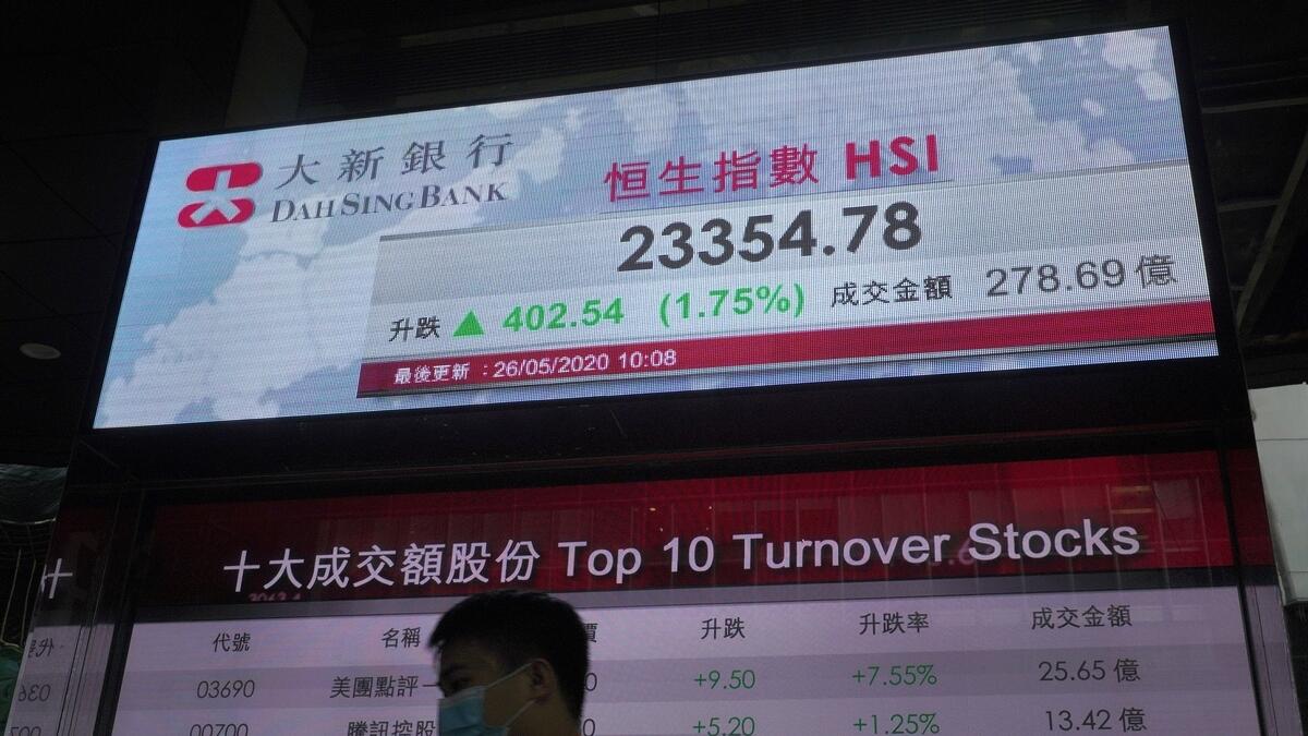 A man wearing face mask walks past a bank electronic board showing the Hong Kong share index at Hong Kong Stock Exchange on Tuesday.