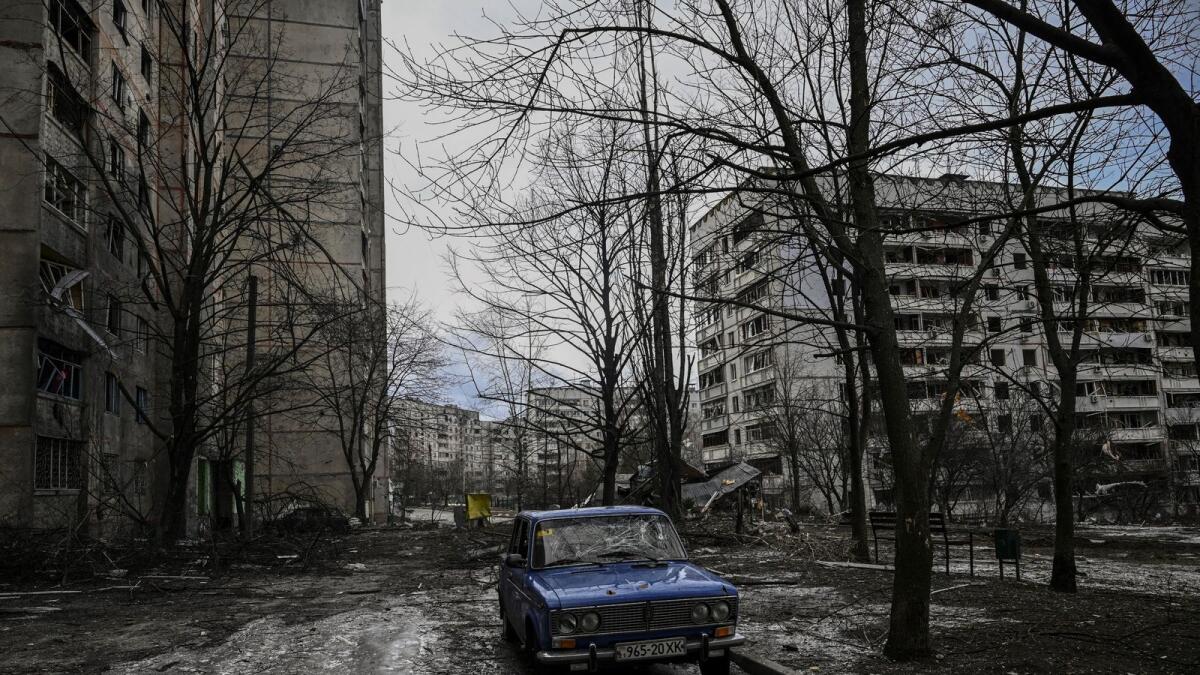 An abandonned car is seen near a damaged apartment building is pictured at a front line discrict of Kharkiv on March 27, 2022, amid Russian attack on Ukraine. Photo: AFP