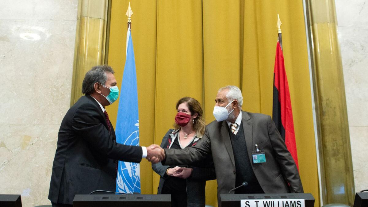 Head of the Libyan Arab Armed Forces delegation A. Amhimmid Mohamed Alamami (left) and Head of the Government of National Accord's military delegation Ahmed Ali Abushahma shaking hands next to deputy special representative of the UN Secretary-General for Political Affairs in Libya Stephanie Williams in Geneva.