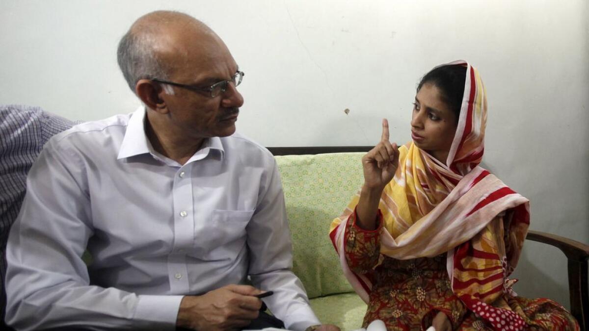 Prabhat K. Jain (L), second secretary at the High Commission of India in Pakistan, shows Geeta, the pictures of families in India who have claimed to be her parents and siblings, during his visit to the Bilquis Edhi Foundation in Karachi, Pakistan.