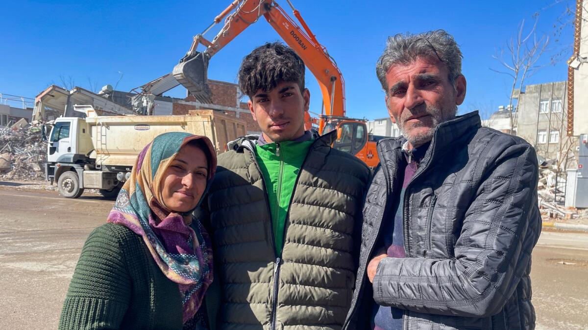 Taha Erdem, 17, centre, his mother Zeliha Erdem, left, and father Ali Erdem pose for a photograph next to the destroyed building where Tahan was trapped after the earthquake of Feb. 6, in Adiyaman, Turkey, on Friday. — AP