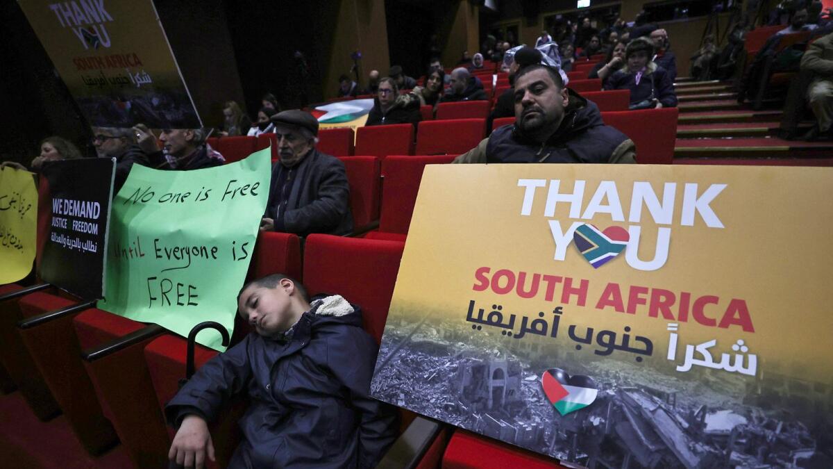 Palestinians lift placards as they attend a live projection of the International Court of Justice (ICJ) hearing of the case brought by South Africa against Israel, attended by the South African Ambassador to Palestine (not pictured) at the Ramallah municipality in the occupied West Bank. — AFP