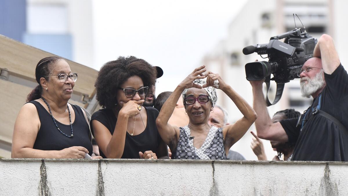 Maria Lucia Nascimento, the sister of the late Brazilian soccer great Pele, signals a heart to people gathered outside her mother's home, during Pele's funeral procession from Vila Belmiro stadium to the cemetery in Santos.