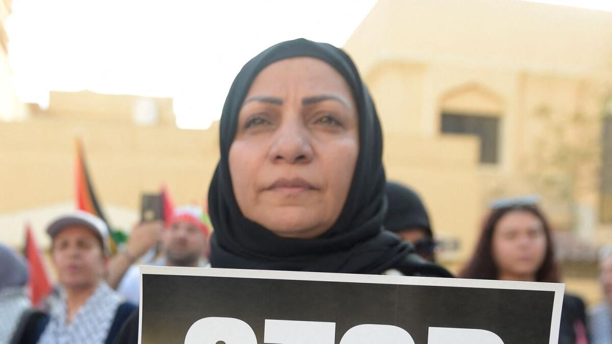 A woman holds a sign during a protest in front of the Palestine Embassy in Manama. — AFP