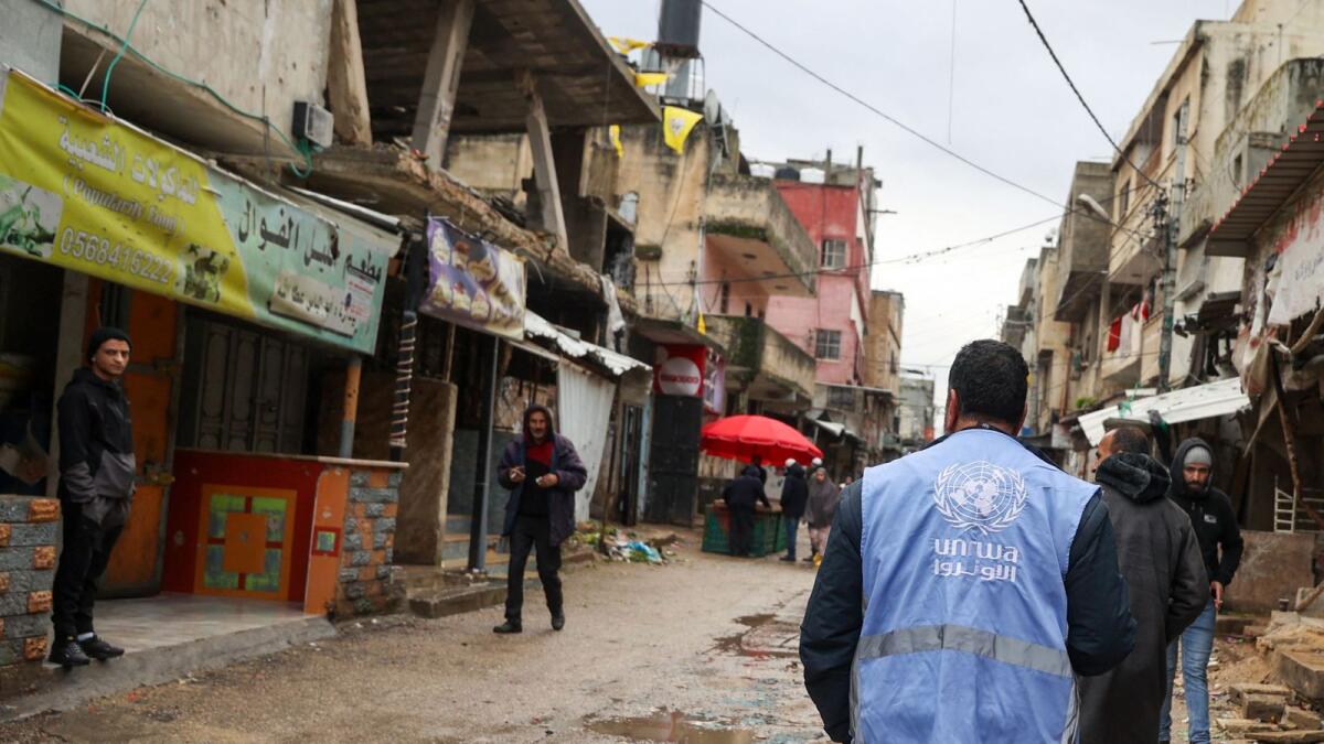 A man wearing a jacket bearing the logo of the United Nations Relief and Works Agency for Palestine Refugees (UNRWA), walks along a street devastated by the passage of Israeli military vehicles and bulldozers during raids. — AFP